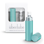 An aqua-colored personal lubricant refillable case, with a 15ml glass insert of uberlube prominently displaying the überlube brand packaging and a capacity indicator at the bottom. — 13