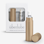 A gold-colored personal lubricant refillable case, with a 15ml glass insert of uberlube prominently displaying the überlube brand packaging and a capacity indicator at the bottom. — 18