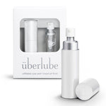 A white-colored personal lubricant refillable case, with a 15ml glass insert of uberlube prominently displaying the überlube brand packaging and a capacity indicator at the bottom. — 16