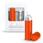 An orange-colored personal lubricant refillable case, with a 15ml glass insert of uberlube prominently displaying the überlube brand packaging and a capacity indicator at the bottom. — 20