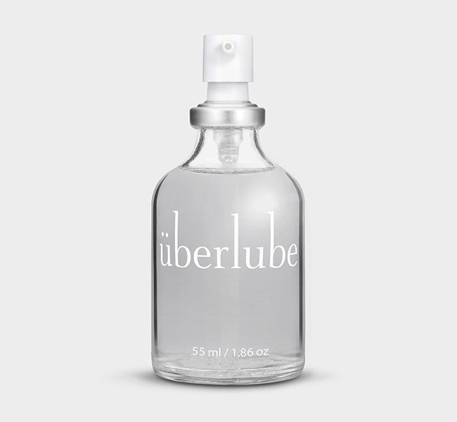 A clear glass bottle with a white spray nozzle, labeled 'Uberlube' and marked with a volume of 55 ml / 1.86 oz. — 10